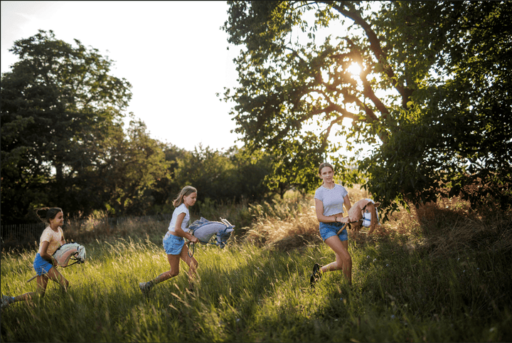 Enfants courant avec des Hobby Horses dans un champ herbeux ensoleillé