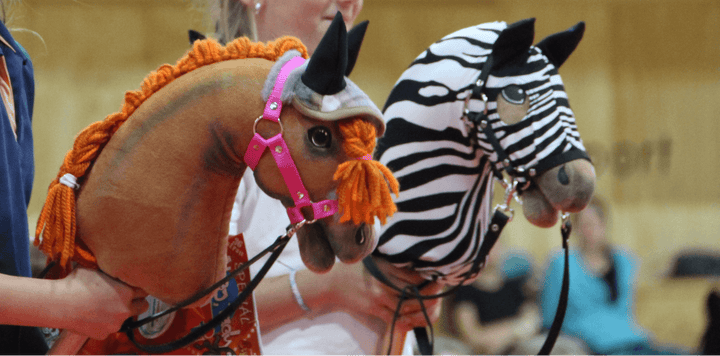 Deux Hobby Horses aux crinières tressées, l’un marron avec du fil orange et l’autre à motif zèbre