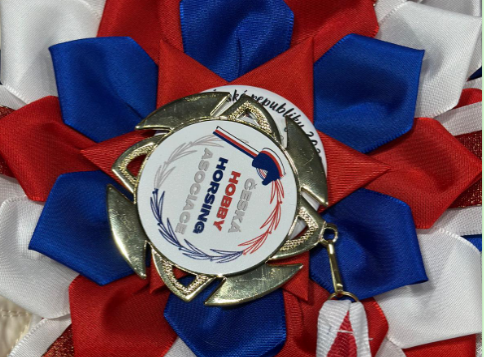 Gros plan sur une cocarde rouge, blanche et bleue avec une médaille dorée et un emblème central de Hobby Horsing, photographiée comme un détail festif du Championnat tchèque de Hobby Horsing 2025.