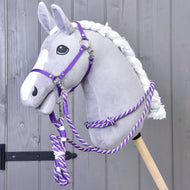 Un Hobby Horse gris en peluche, liste blanche et crinière tressée, porte le licol violet et les rênes en corde du Set Start Violet