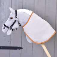 Een grijze pluche Hobby Horse met zwarte halster draagt de deken omgekeerd met de effen lichte kant buiten en karamelkleurige bies