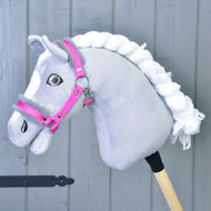 Un Hobby Horse gris en peluche à crinière blanche tressée et yeux marron porte le licol rose vif à fourrure grise