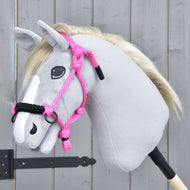Hobby Horse gris clair à crinière blonde avec le licol en corde rose à muserolle noire, devant une porte en bois grise