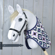 Hobby Horse gris à crinière crème et licol noir portant la couverture Indian, vu de face devant une porte en bois grise