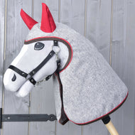 Grijze Hobby Horse met zwart halster in de grijs gemêleerde regenjas met rode oren over hoofd en hals