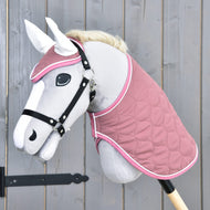 Hobby Horse gris clair avec licol noir portant la couverture matelassée vieux rose et le bonnet d’oreilles aux oreilles blanches