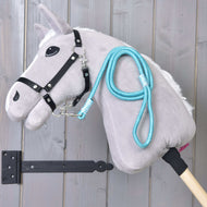 Lichtgrijze Hobby Horse met zwart halster en het turquoise gestreepte halstertouw Atlantis over de hals