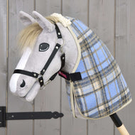 Hobby Horse en peluche grise avec licol noir portant la couverture d’écurie à carreaux bleu clair, sangle de poitrail noire fermée