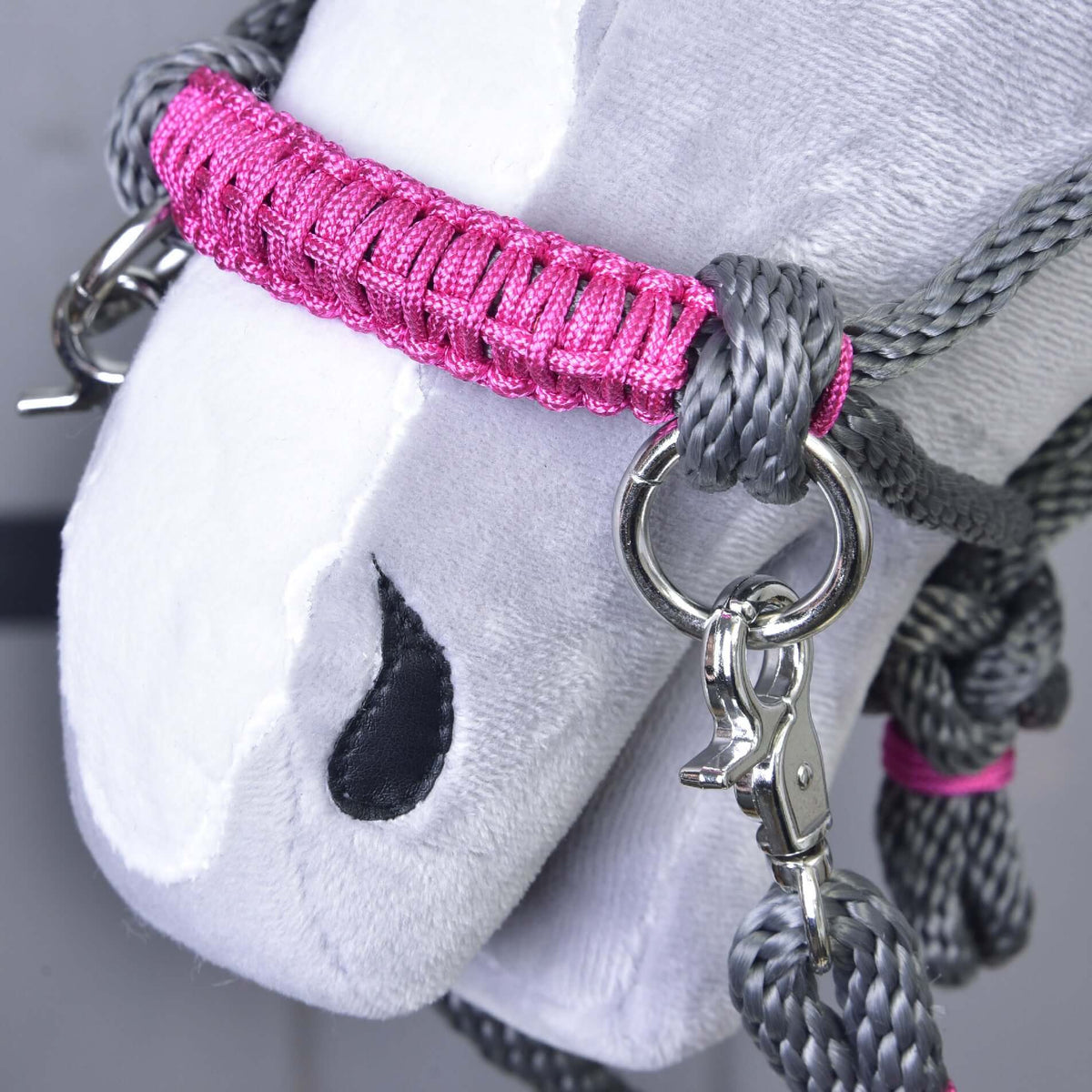 Gros plan sur la muserolle gainée de rose, l’anneau argenté et le mousqueton du licol en corde gris d’un Hobby Horse