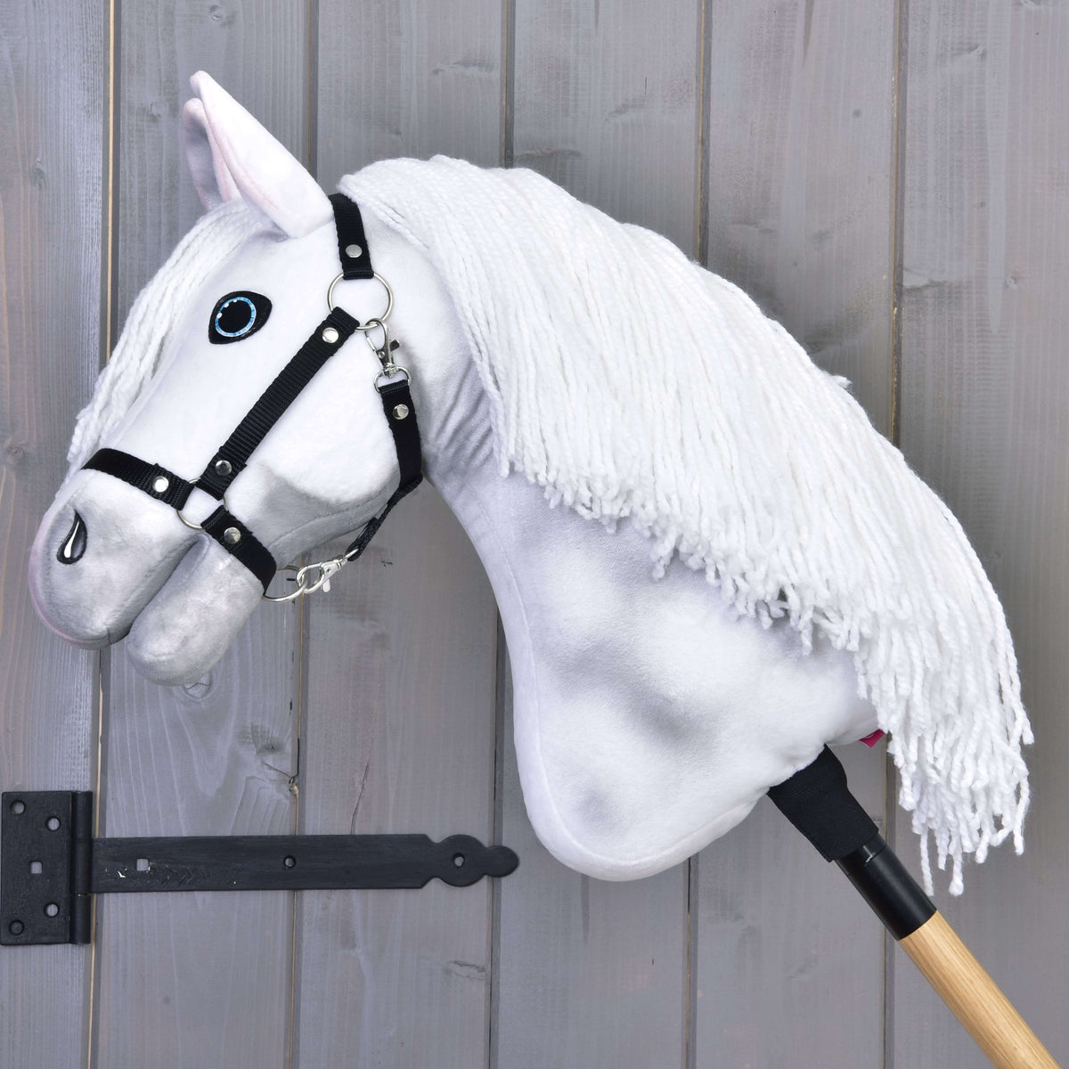 Hobby Horse Elektra avec licol noir, tête baissée, épaisse crinière en fil blanc tombant sur l’encolure