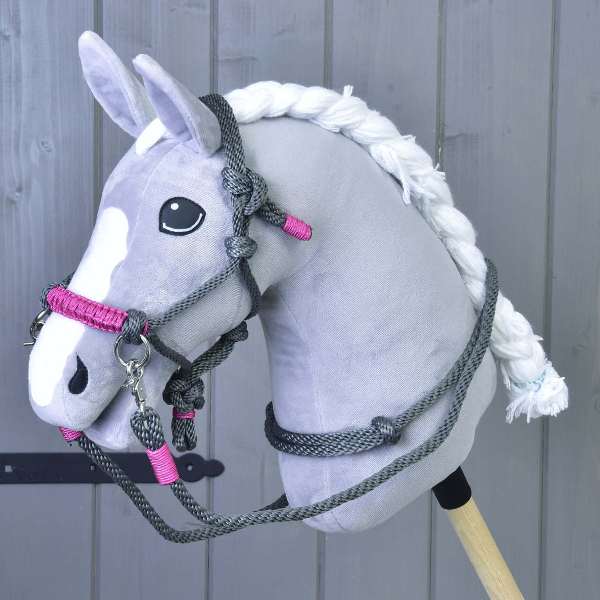 Hobby Horse gris à crinière blanche tressée portant le licol en corde gris à muserolle rose et des rênes en corde grises
