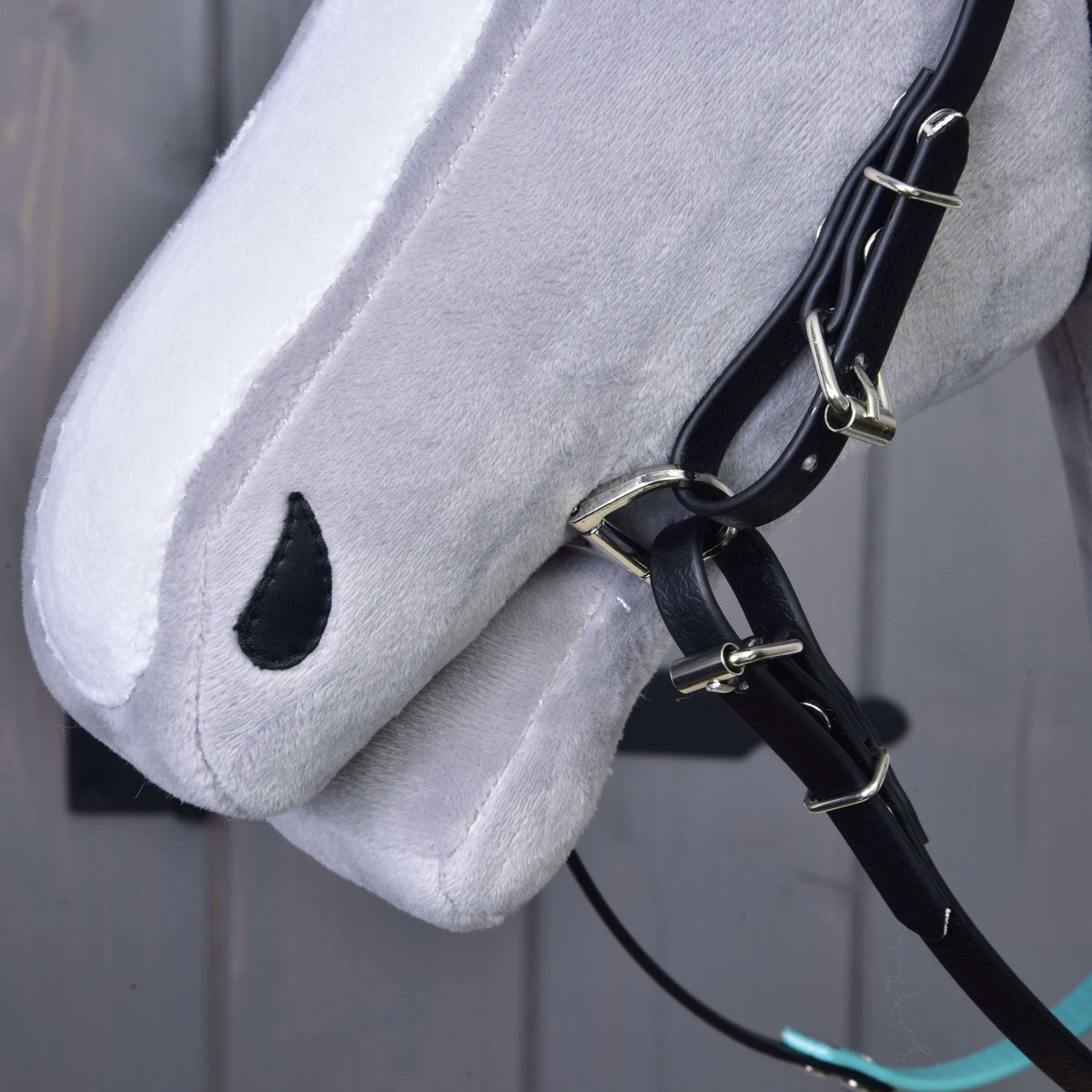 Gros plan sur le bout du nez d'un Hobby Horse gris avec montants noirs, boucles et anneau de mors, sans muserolle