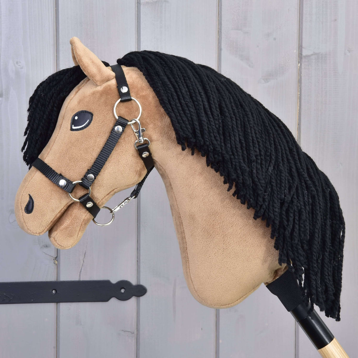 Hobby Horse Samantha van opzij met zwart halster, zilveren ringen en musketonhaak en lange zwarte manen van garen