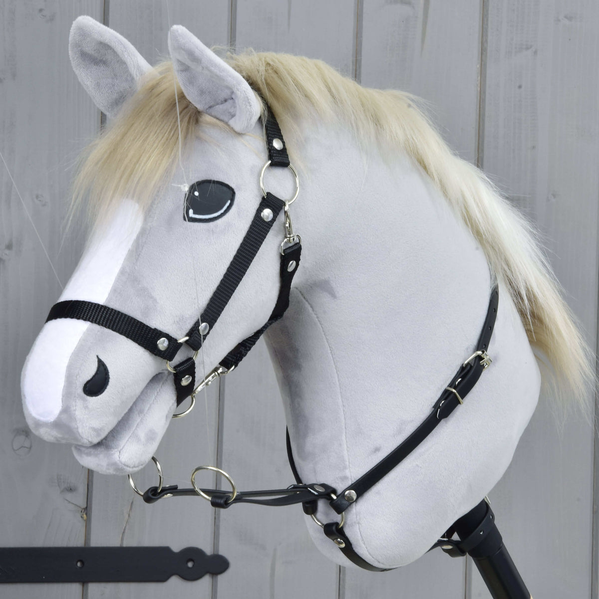 Light grey Hobby Horse in a black halter wearing the Martingale black around its neck, two silver rings in front