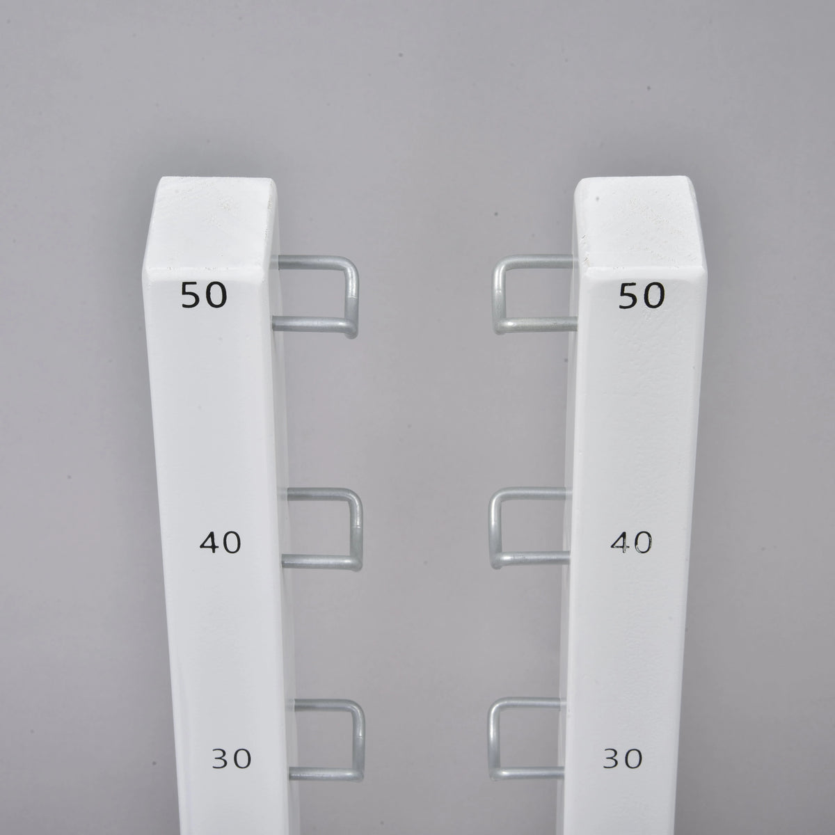 Close-up of the two stand tops with black 30, 40 and 50 marks and U-shaped metal hooks facing each other