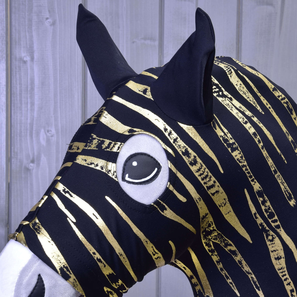 Gros plan sur les rayures zèbre dorées, les oreilles noires et l’ouverture pour l’œil de la combinaison de protection en Lycra sur un Hobby Horse