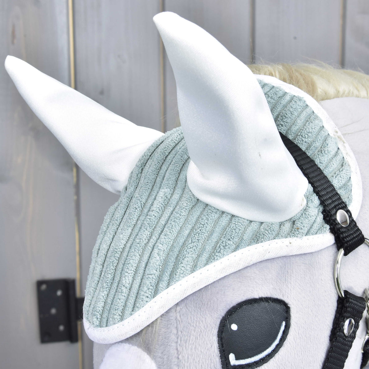 Gros plan sur le bonnet d’oreilles Manchester Little Green, oreilles en satin blanc et bordure blanche sur velours côtelé vert sauge