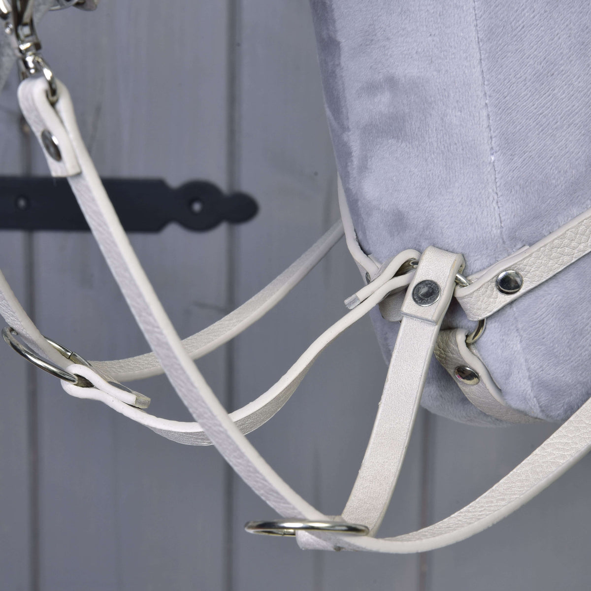 Close-up of the cream martingale rings with the reins running through them under a grey Hobby Horse neck