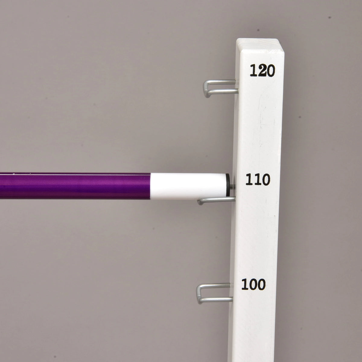 A purple pole with a white end resting on the metal hook at 110 cm of a tall white stand