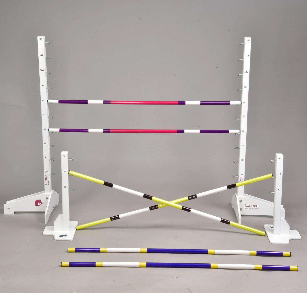The set built as a cross: two yellow and black poles crossed on the low stands, purple-pink poles on the tall ones