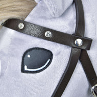 Gros plan sur le frontal en similicuir marron foncé orné de diamants scintillants, au-dessus de l’œil d’un Hobby Horse gris clair