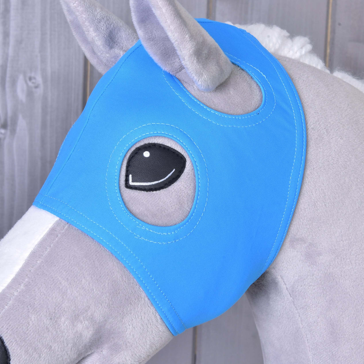 Close-up van het paardenmasker zonder oren Sky op een grijze Hobby Horse, de openingen rond het pluche oor en het zwarte oog
