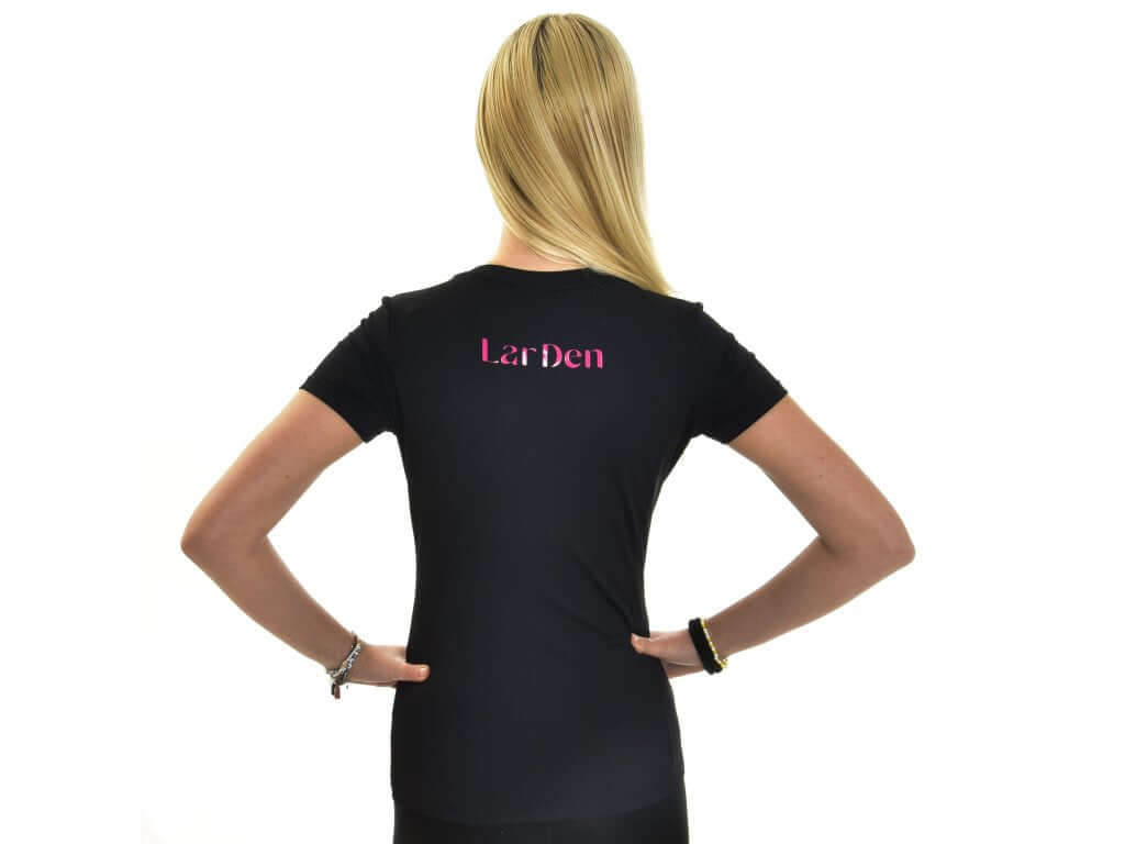 Jeune fille blonde vue de dos, mains sur les hanches, en T-shirt Active Hobby Horse noir à inscription rose dans le dos