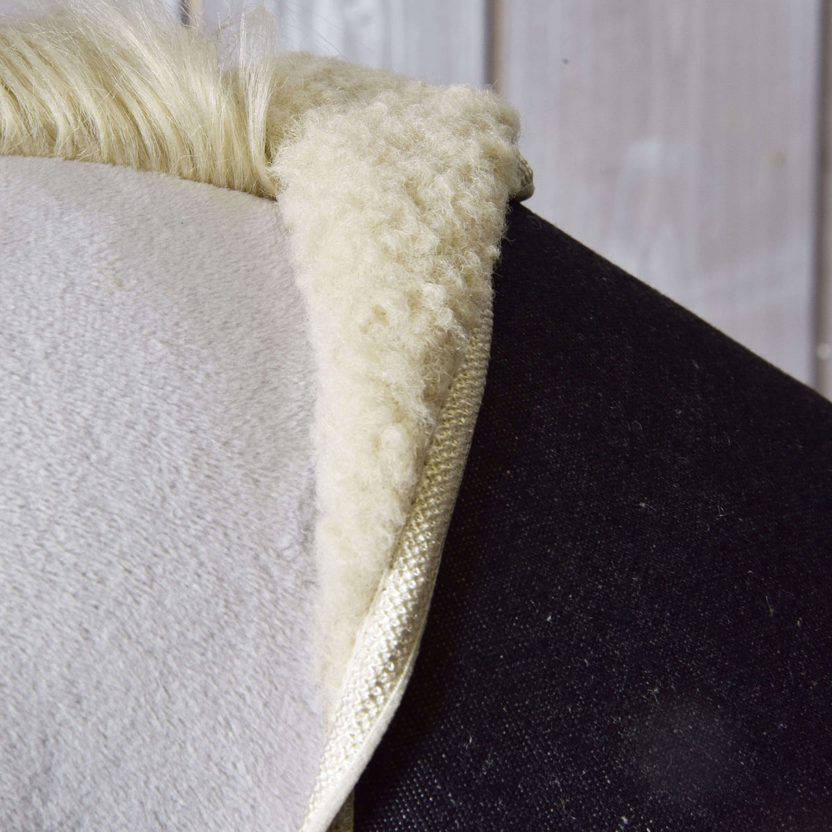 Close-up of the cream sherpa collar where the dark denim blanket meets the grey plush neck and blond mane