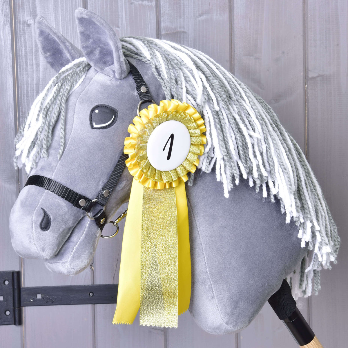Première place : la cocarde jaune et or numéro 1 épinglée à l’encolure d’un Hobby Horse gris au licol noir