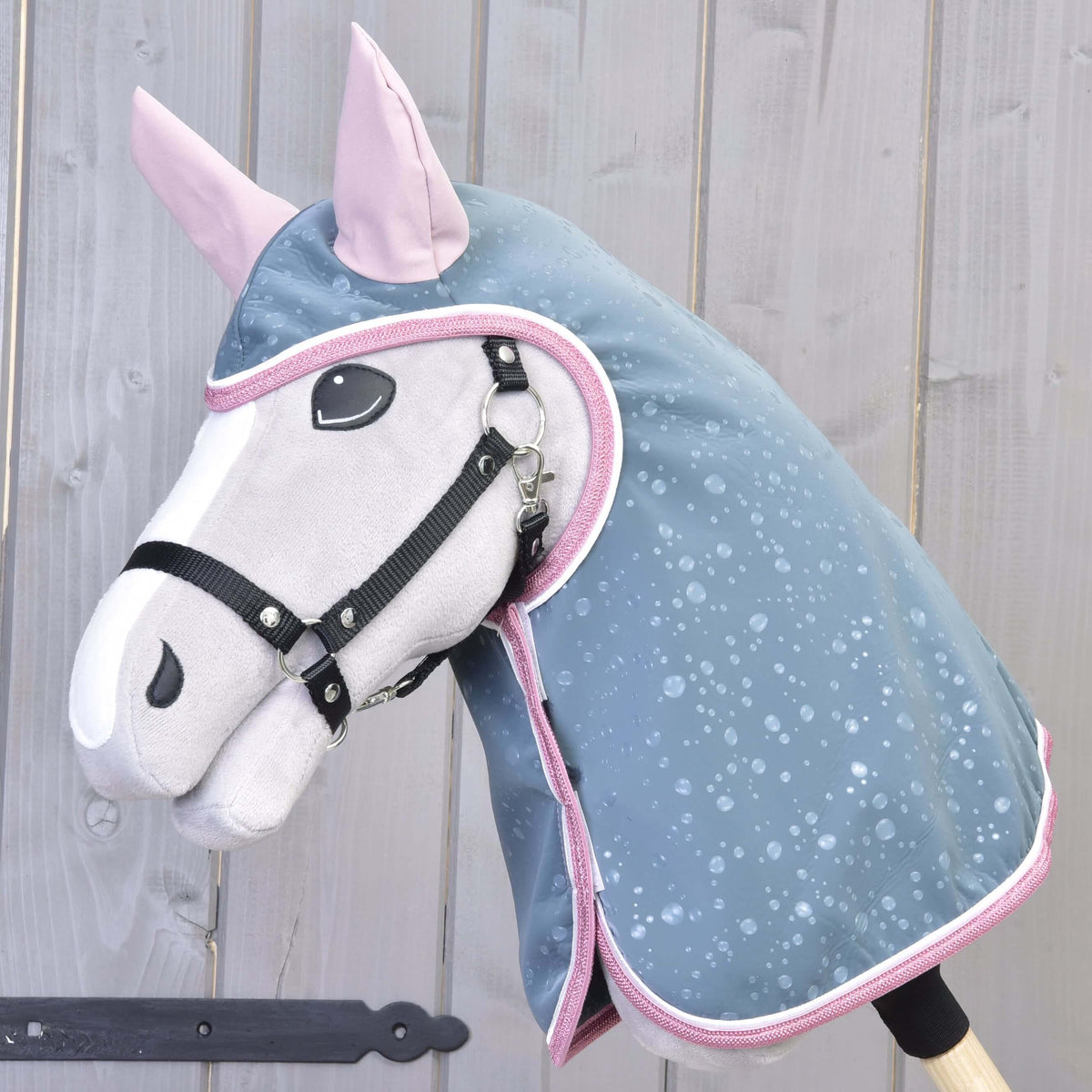 Dichtbij de capuchon van de regenjas met roze oren en roze bies rond het hoofd van een grijze Hobby Horse