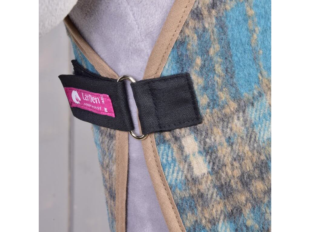 Close-up of the black front strap with a pink LarDen label and silver ring on the blue tartan blanket