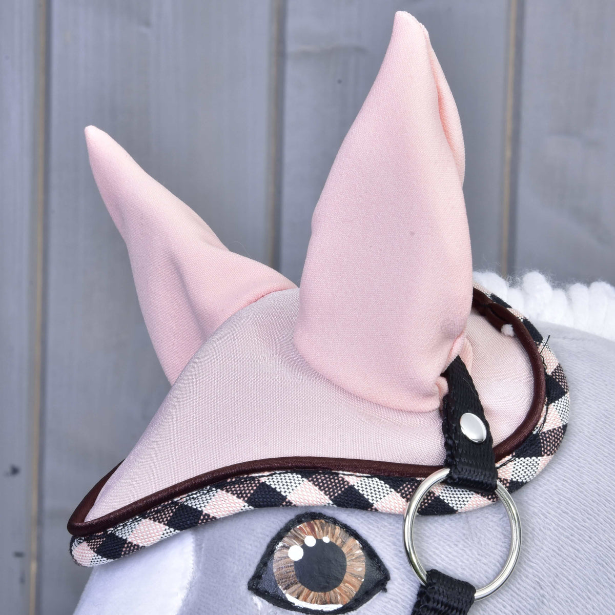Close-up van het oornetje uit de Set Abby op een grijze Hobby Horse, met hoge roze oren, bruine bies en zwart-wit-roze geruite rand
