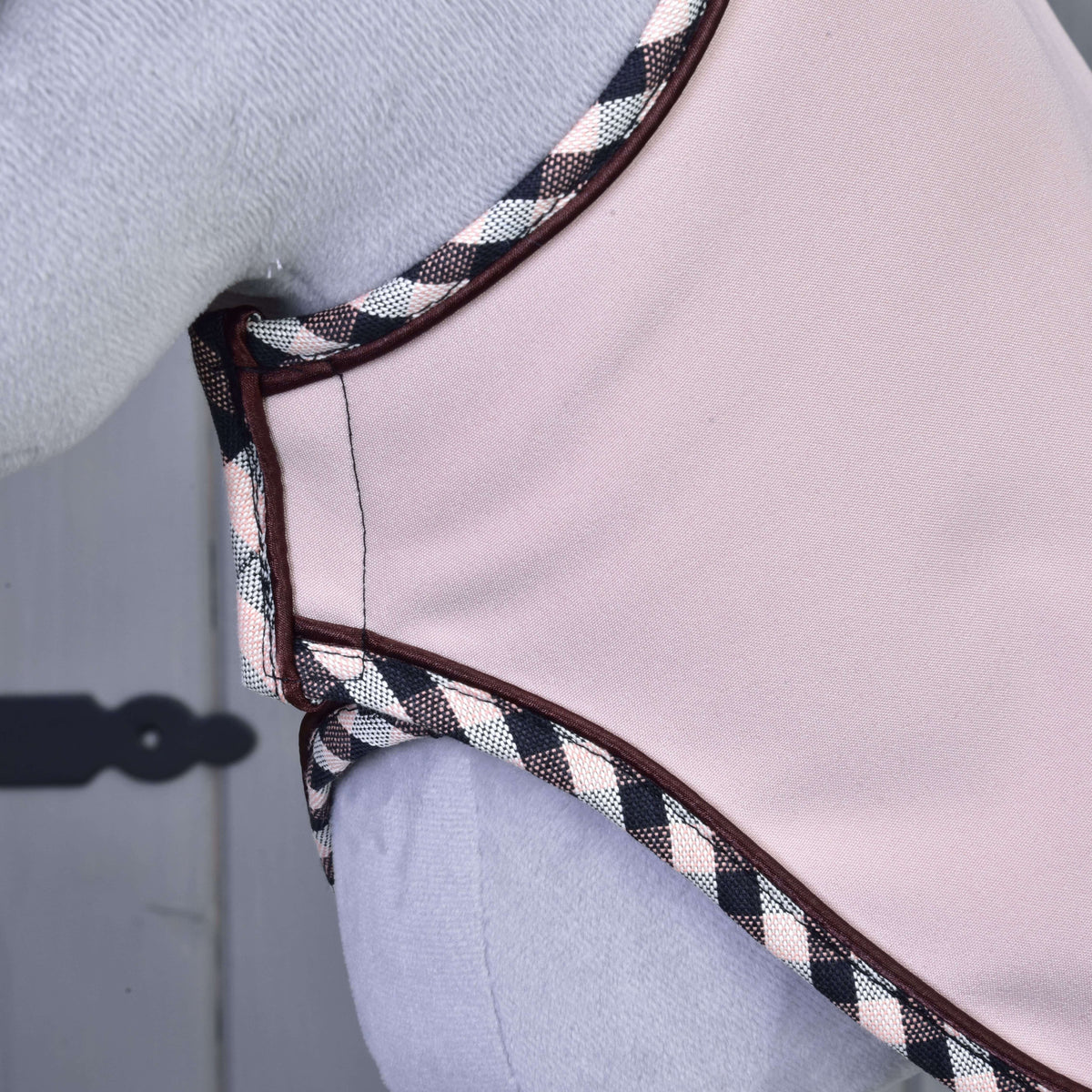 Close-up van de lichtroze deken uit de Set Abby bij de borst van een grijze Hobby Horse, met geruite rand en fijne bruine bies