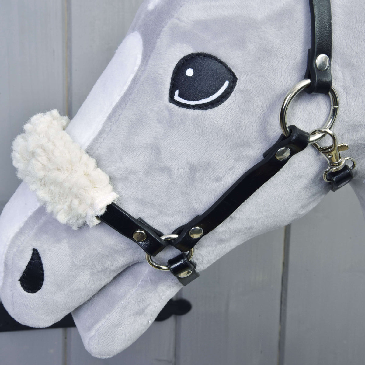 Detail van het halster uit de Set Basic op een Hobby Horse: zwarte riemen, zilveren ringen en zacht crème bont op de neusriem