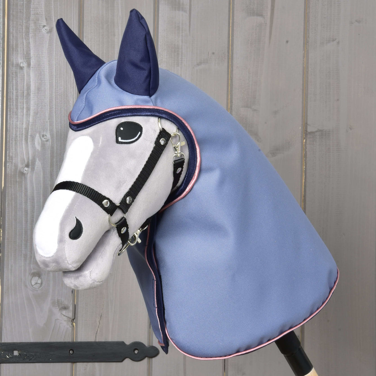 Hobby Horse gris avec licol noir portant l’imperméable Bloom à capuche et oreilles bleu marine, bleu clair à passepoil rose