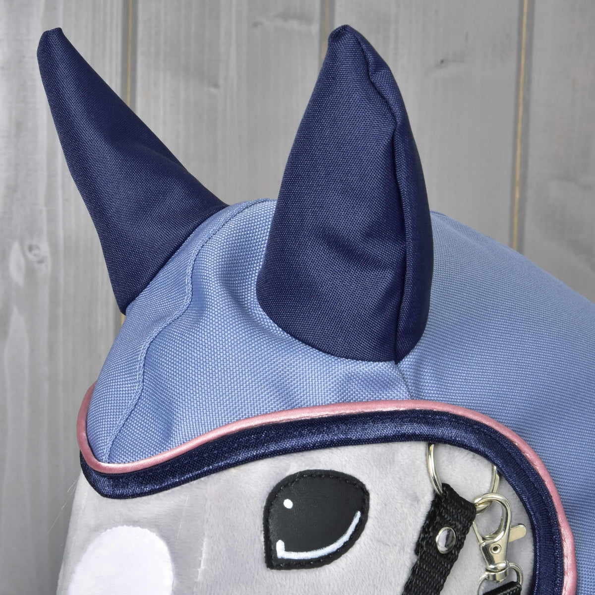 Gros plan sur la capuche de l’imperméable Bloom pour Hobby Horse : oreilles bleu marine sur tissu bleu clair et passepoil rose autour du visage