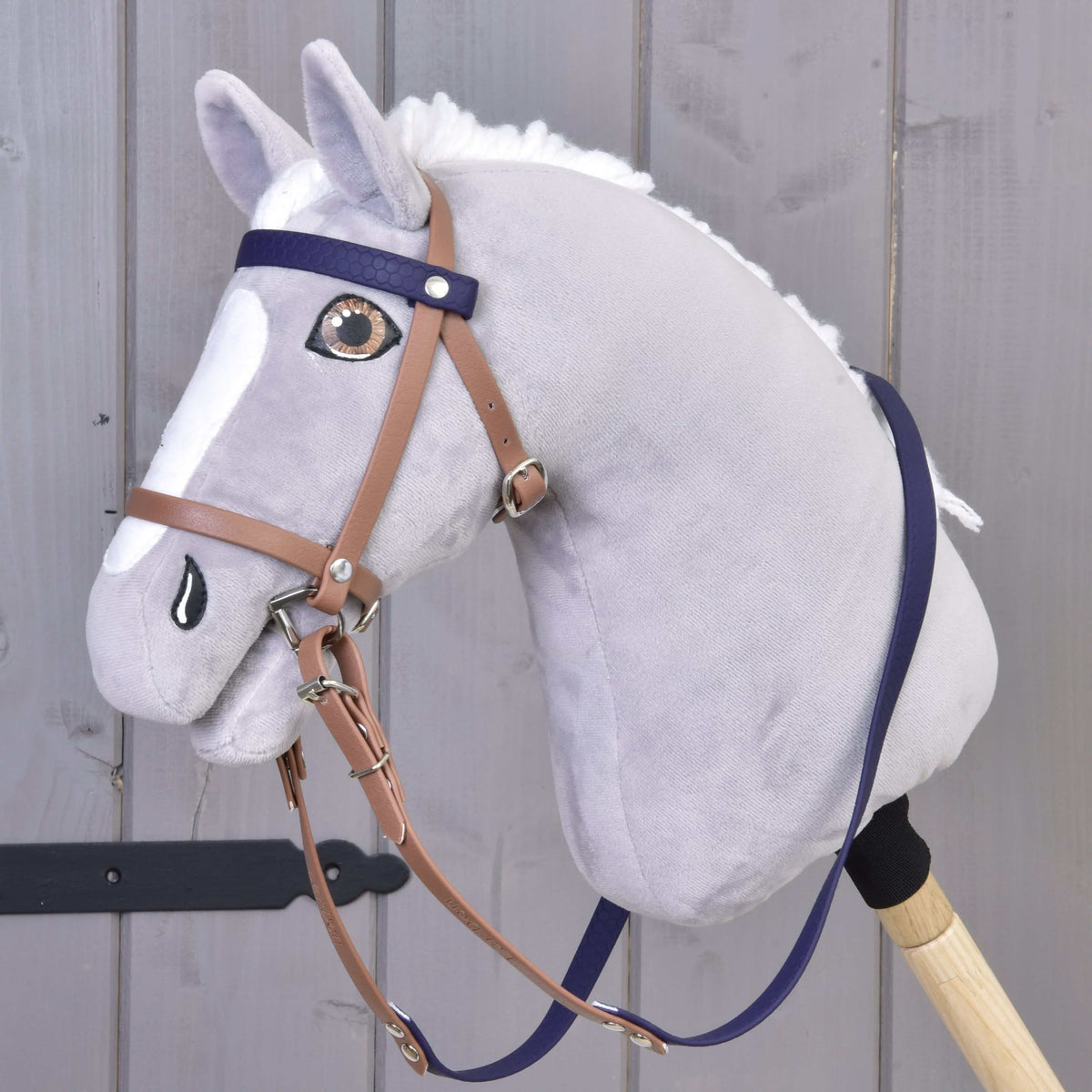 Bride complète avec muserolle Brown Purple LarDen sur un Hobby Horse gris, montants havane avec frontal et rênes violets