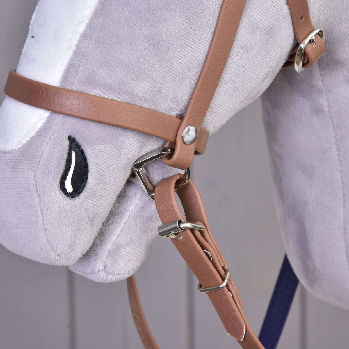 Gros plan sur la muserolle havane en similicuir avec boucles argentées et attache des rênes sur le nez d’un Hobby Horse gris
