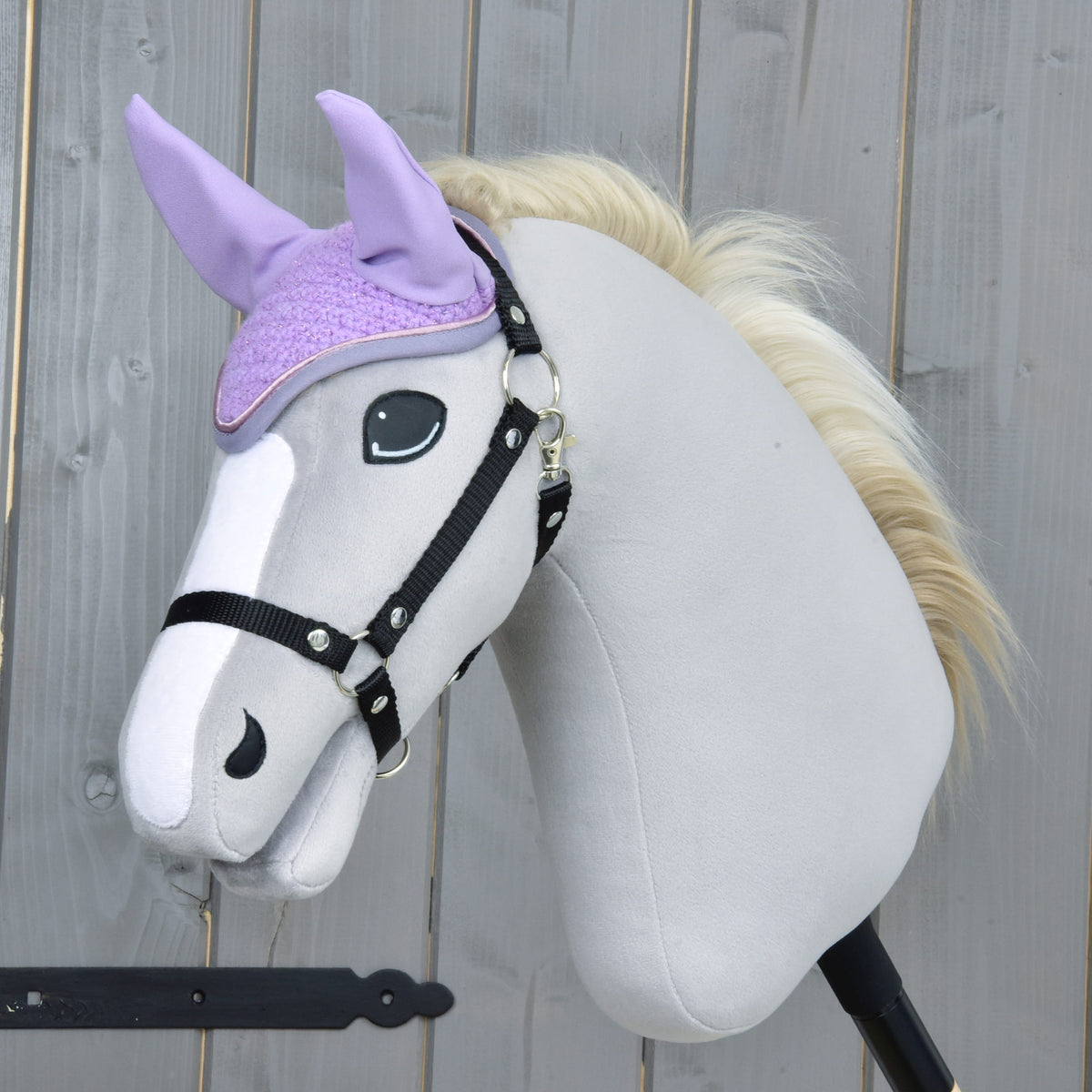 Lichtgrijze Hobby Horse met zwart halster en crèmekleurige manen draagt het lila gehaakte oornetje