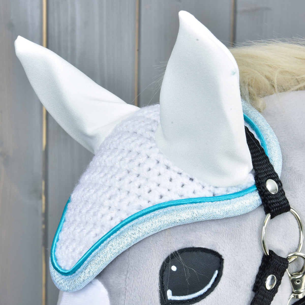 Close-up of the white crochet stitches, satin ears and glittery pale blue edge with turquoise piping above the eye