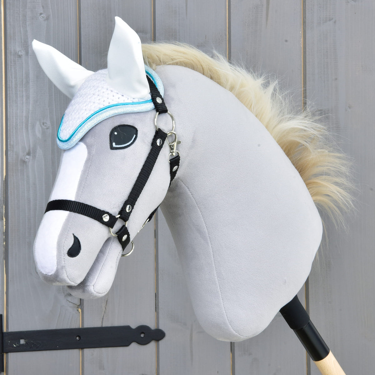 Light grey Hobby Horse with a black halter and cream mane wearing the white crocheted ear bonnet with turquoise trim