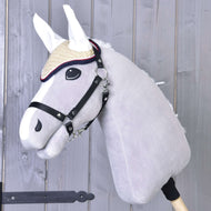 Grijze Hobby Horse met zwarte halster draagt het crèmekleurige gehaakte oornetje Nicol met witte oren en rood-donkerblauwe rand