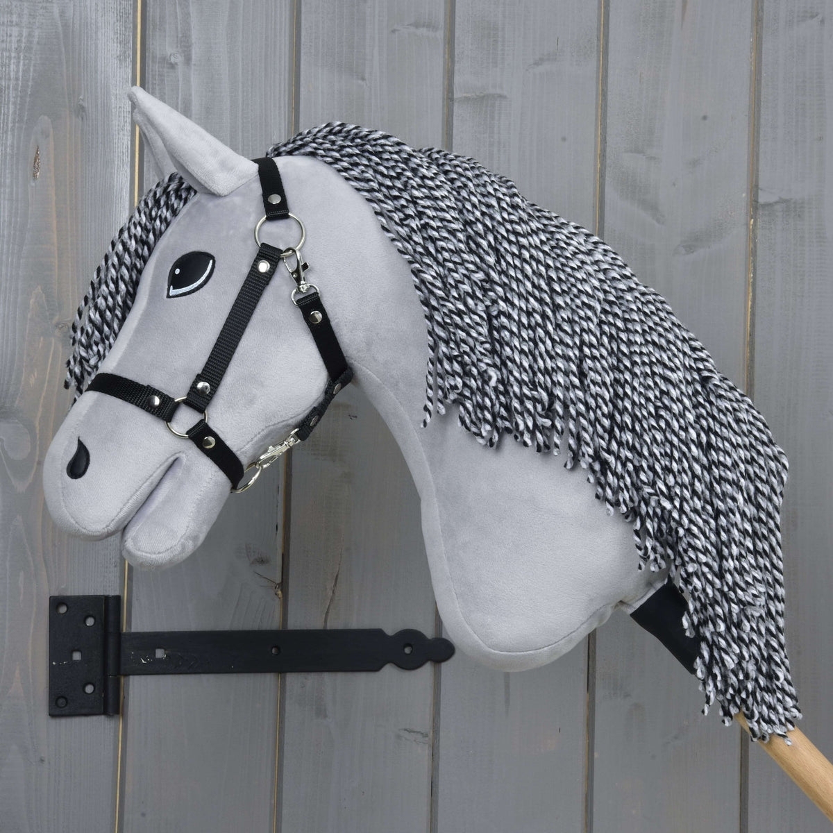 Hobby Horse Caesar de profil gauche, sa longue crinière torsadée noire et blanche en fil sur l’encolure gris clair