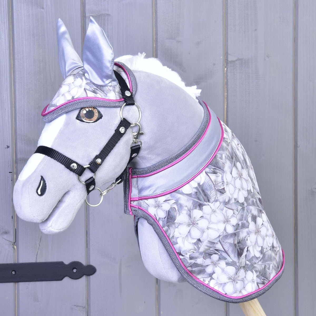 Hobby Horse gris aux yeux ambre avec licol noir portant l’ensemble Grey Flower, couverture et bonnet d’oreilles fleuris à bordure rose