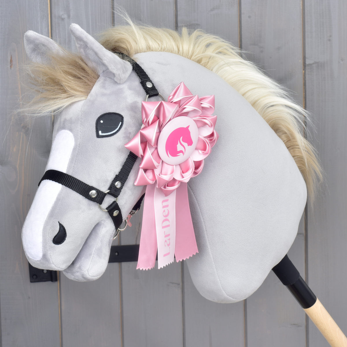 Ruban Hobby Horse LarDen Pink fixé au licol noir d’une tête grise en peluche à liste blanche et crinière blonde