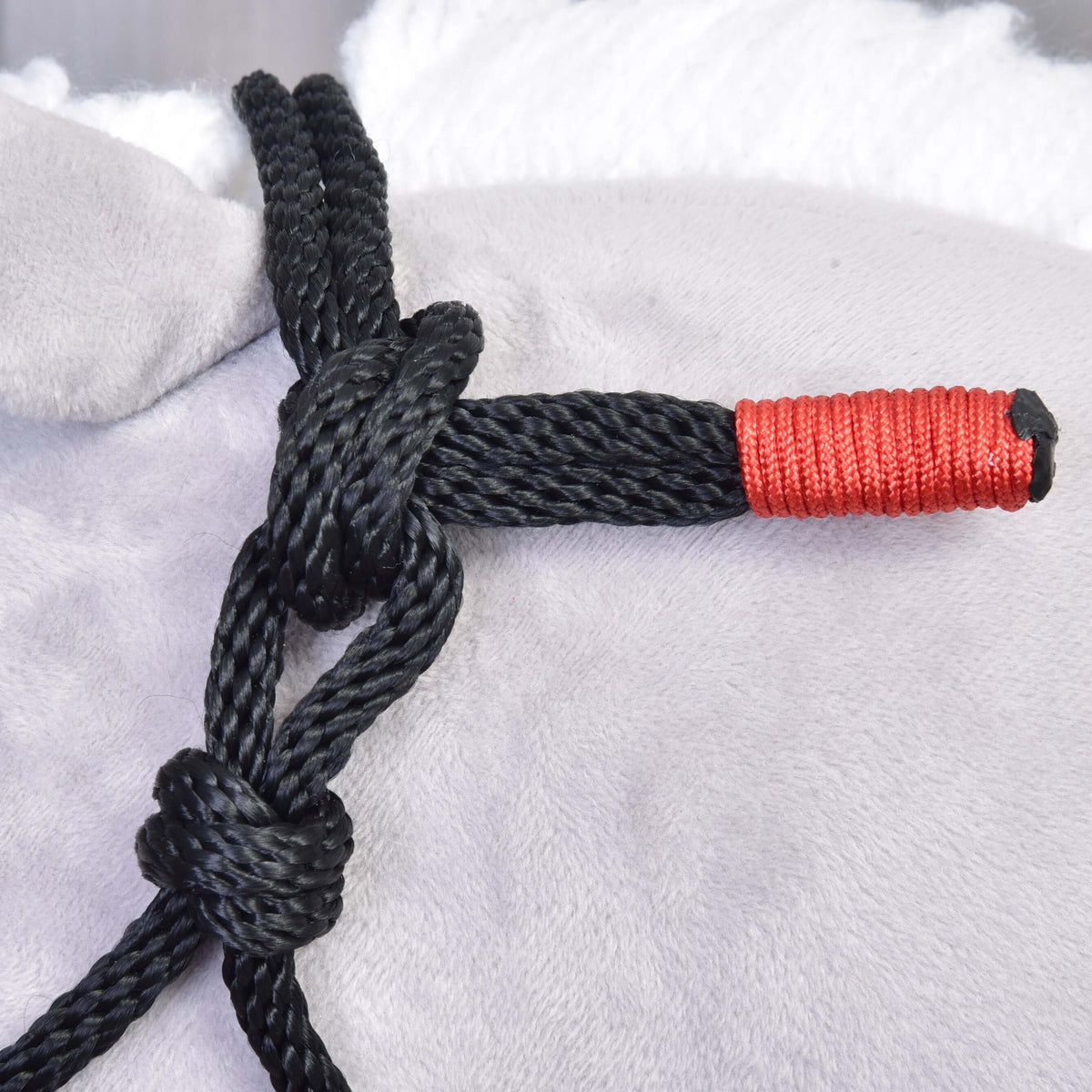 Close-up van de knopen van het zwarte touwhalster met rood omwikkeld uiteinde uit de Touwset Spark voor Hobby Horse