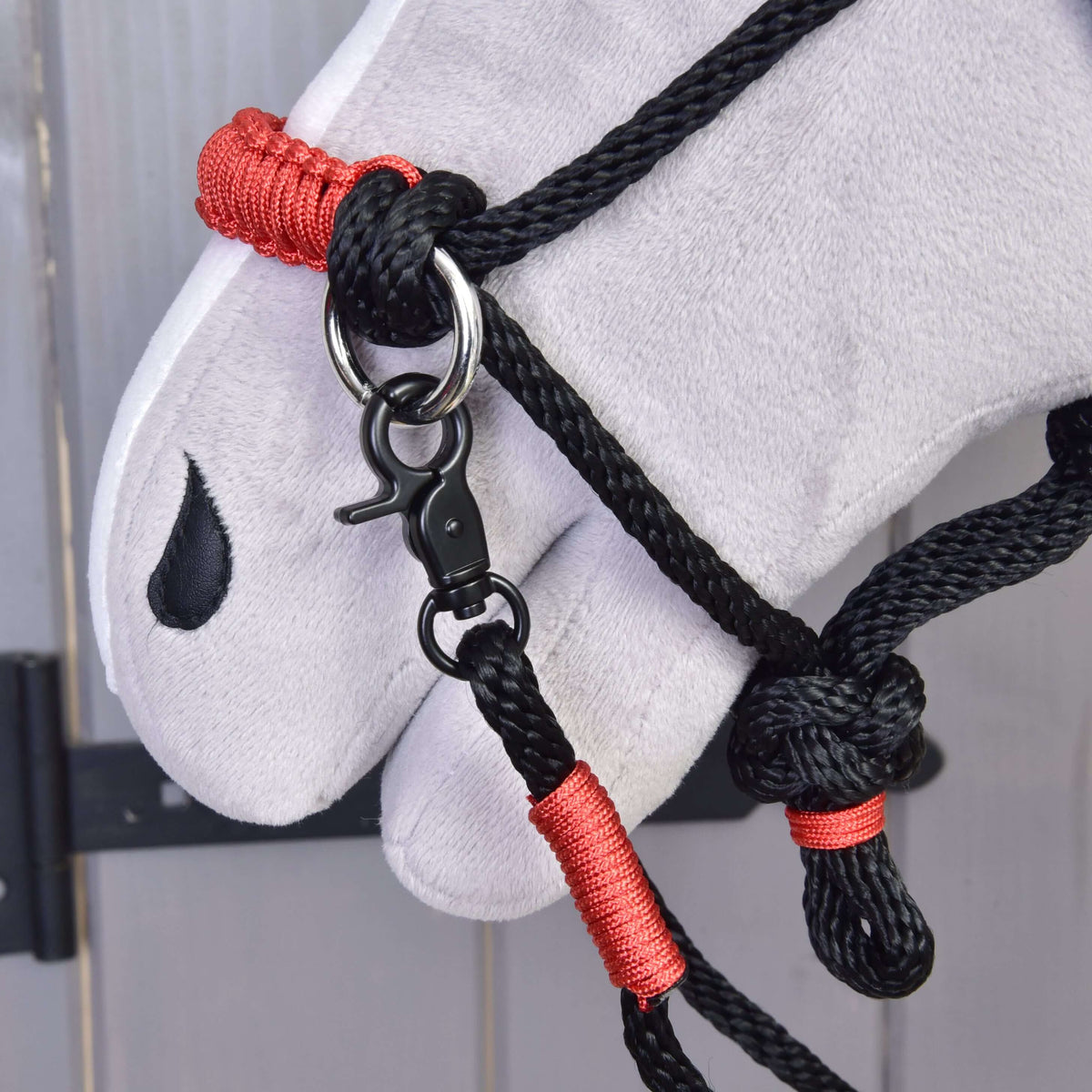 Close-up van de Touwset Spark voor Hobby Horse: rood gevlochten neusriem, zwarte karabijnhaak en rode omwikkelingen