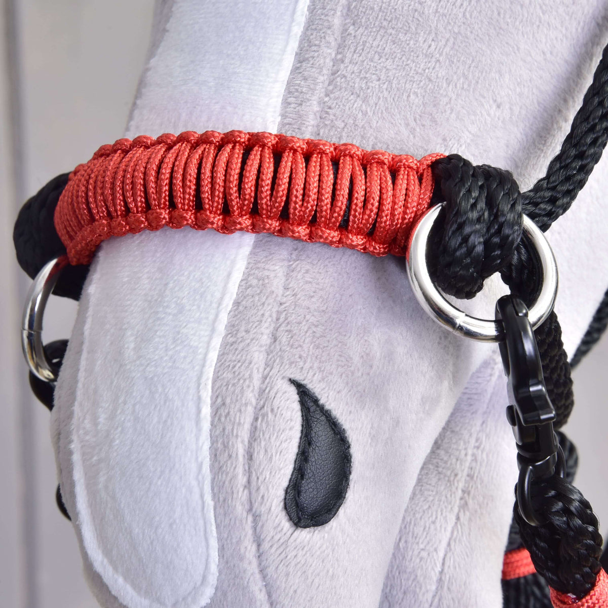 Close-up van de rood gevlochten neusriem met zilveren ringen aan het halster uit de Touwset Spark voor Hobby Horse