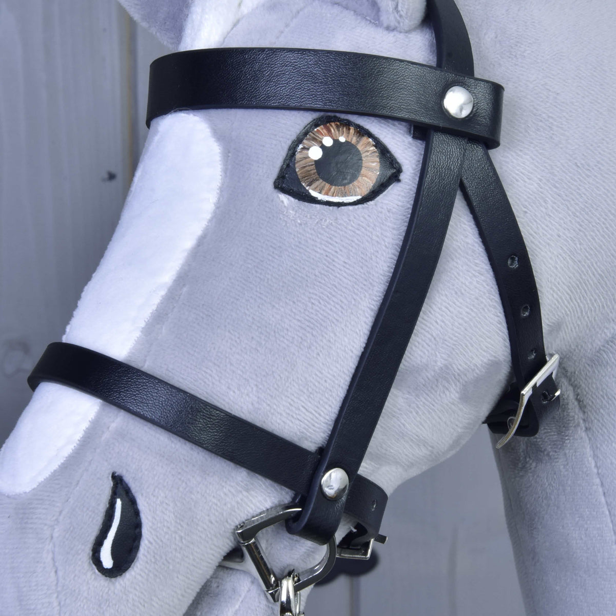 Detail van het zwarte hoofdstel uit de Set Basic op een grijze Hobby Horse met frontriem, zilveren gesp en bruin oog