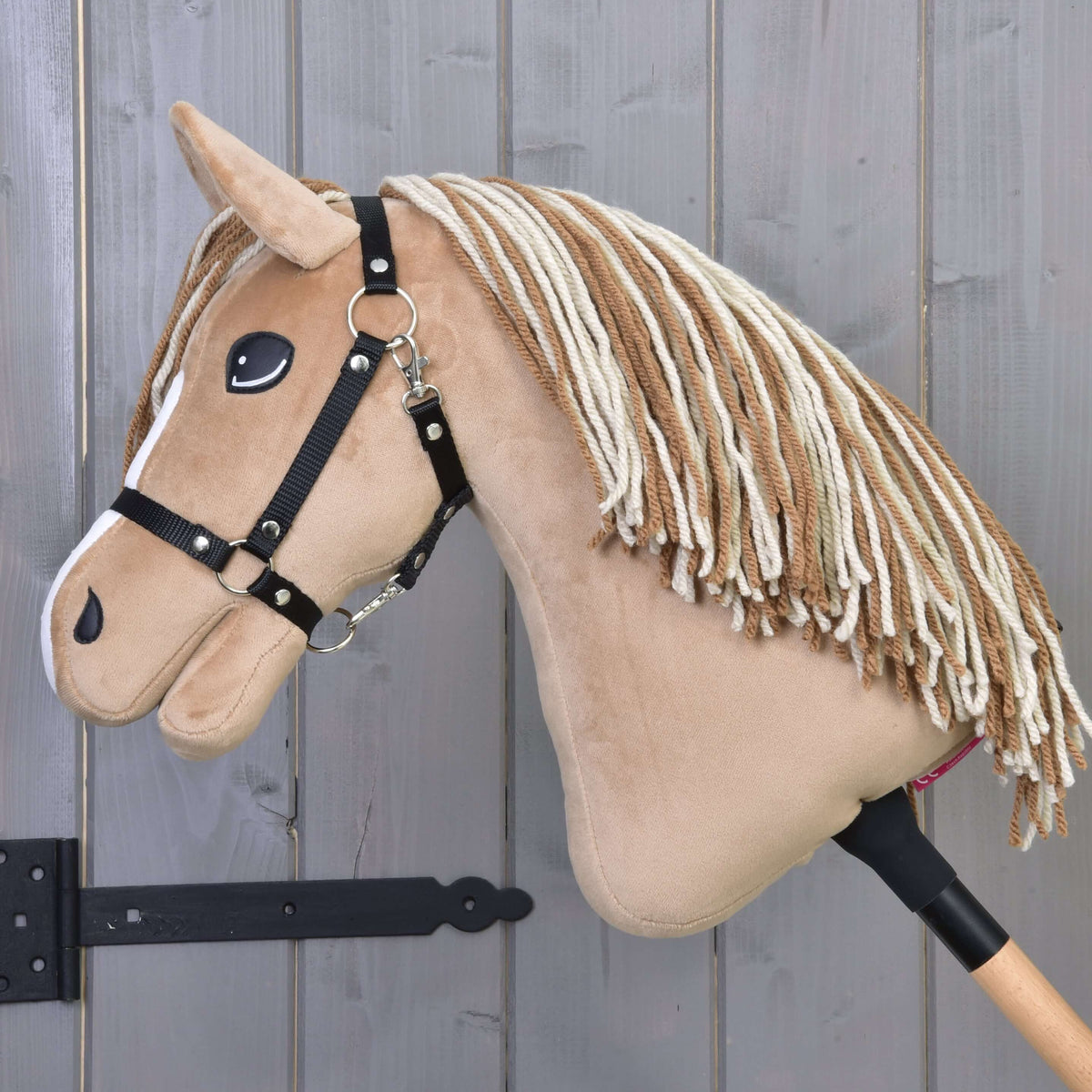 Hobby Horse Bren with Black Halter from the side, head lowered, long brown and cream yarn mane over the tan neck